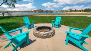 turquoise chairs around fire pit by lake