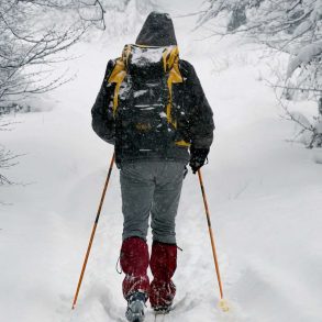 Man trudging through a snow covered trail on skis in West Michigan