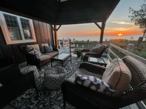 deck with porch furniture overlooking water at sunset