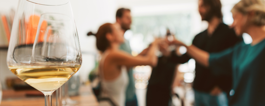 white wine in glass with people toasting in the background