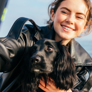 woman taking a selfie with dog on beach