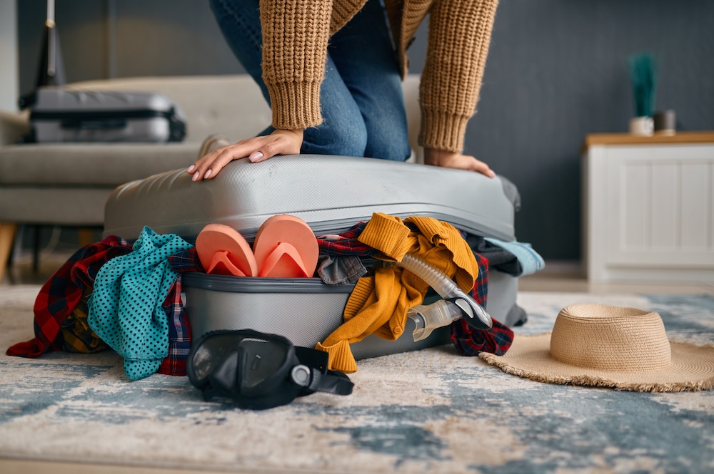 Packing over stuffed suitcase.
