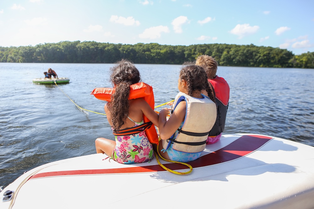 People sitting on a boat and tubing on an inland lake