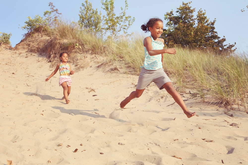 Happy Smiling girls running down the dunes at the beach.